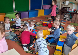 dzieci wspólnie bawią się na dywanie różnymi zabawkami